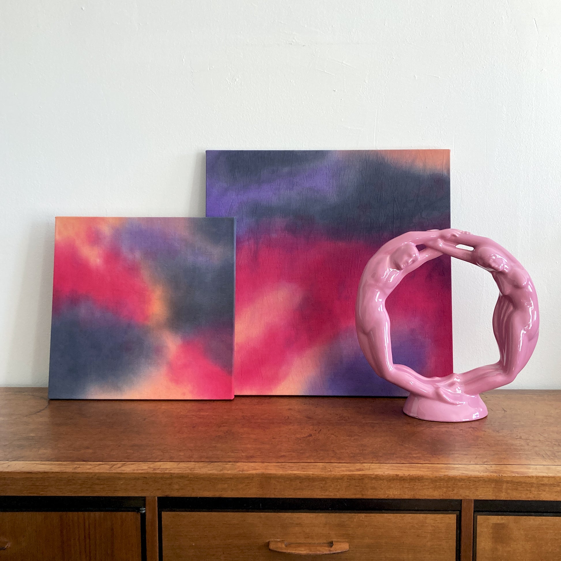 A grouping of abstract cloud paintings in tones of pink, peach and gray.