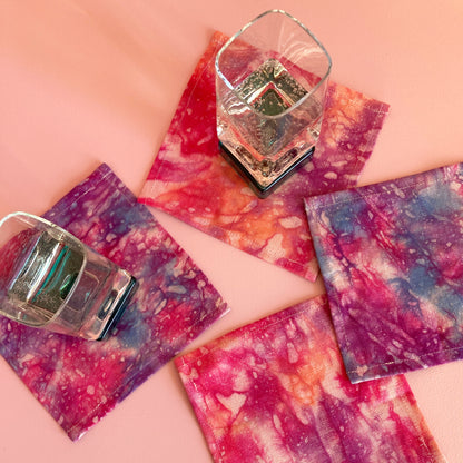 A grouping of hand dyed cocktail napkins in pink, purple, indigo and orange.