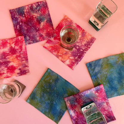 A grouping of hand dyed cocktail napkins in pink, purple, indigo, turquoise and orange.