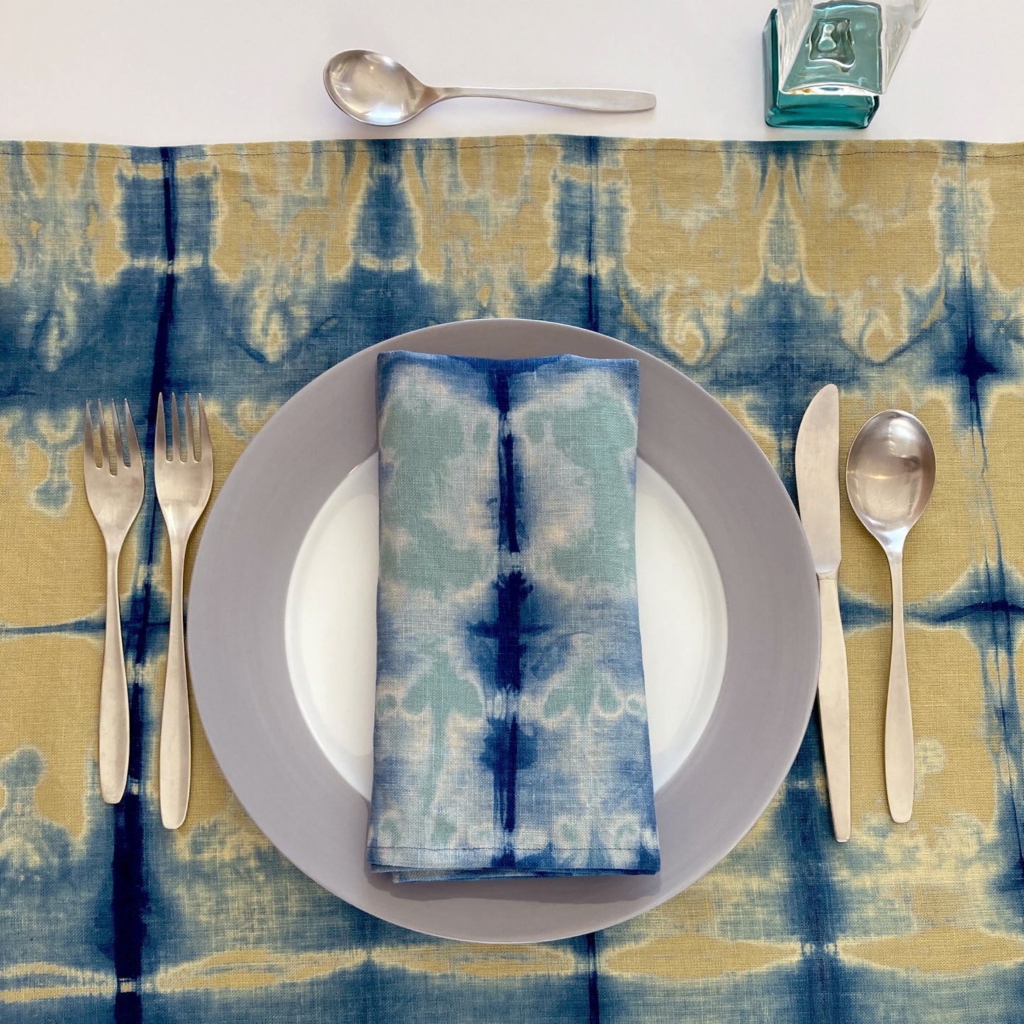 Gold mustard linen table runner dyed with indigo in Pleat pattern, shown here with napkin in jade.