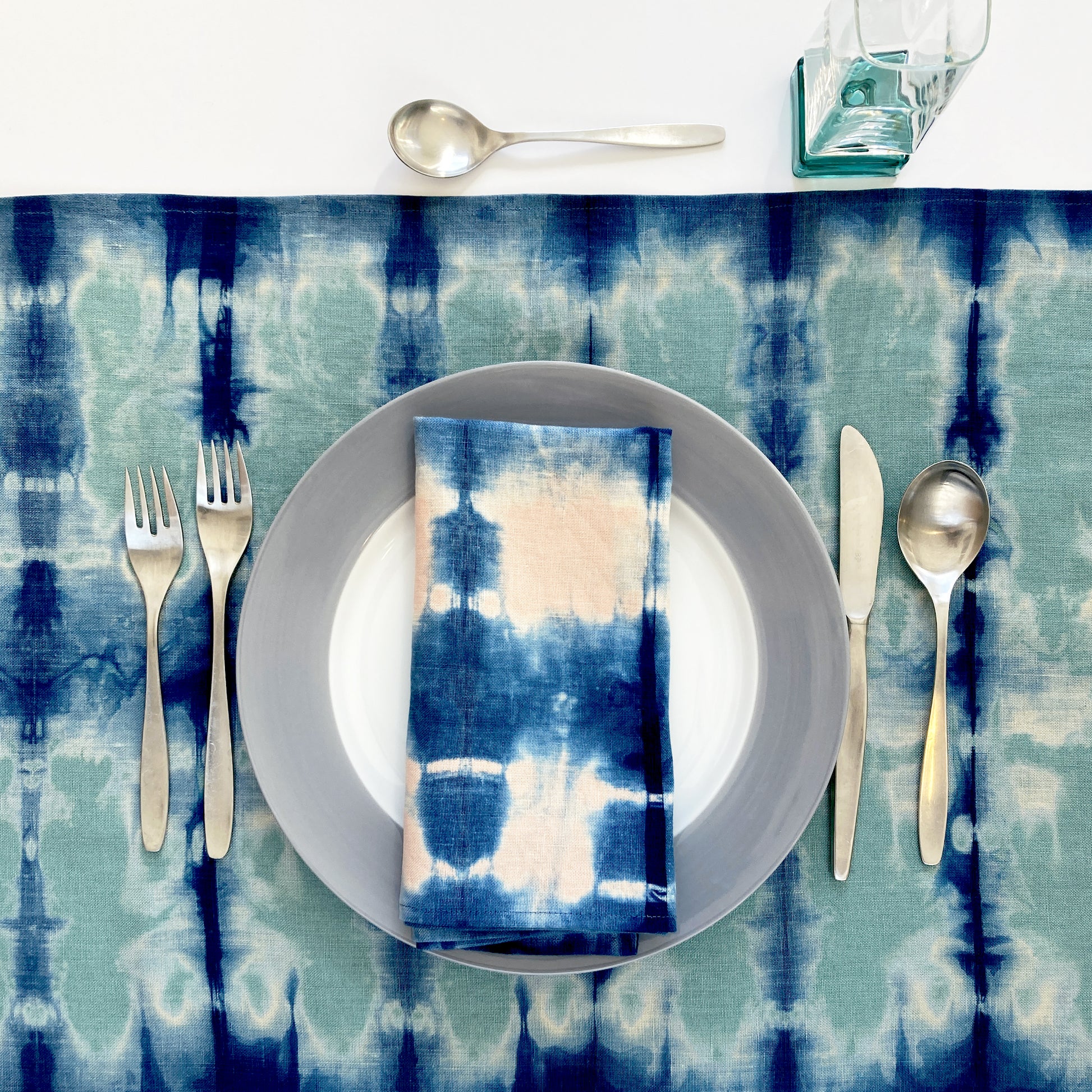 Jade green linen table runner dyed with indigo in Pleat pattern, shown here with napkin in rose.