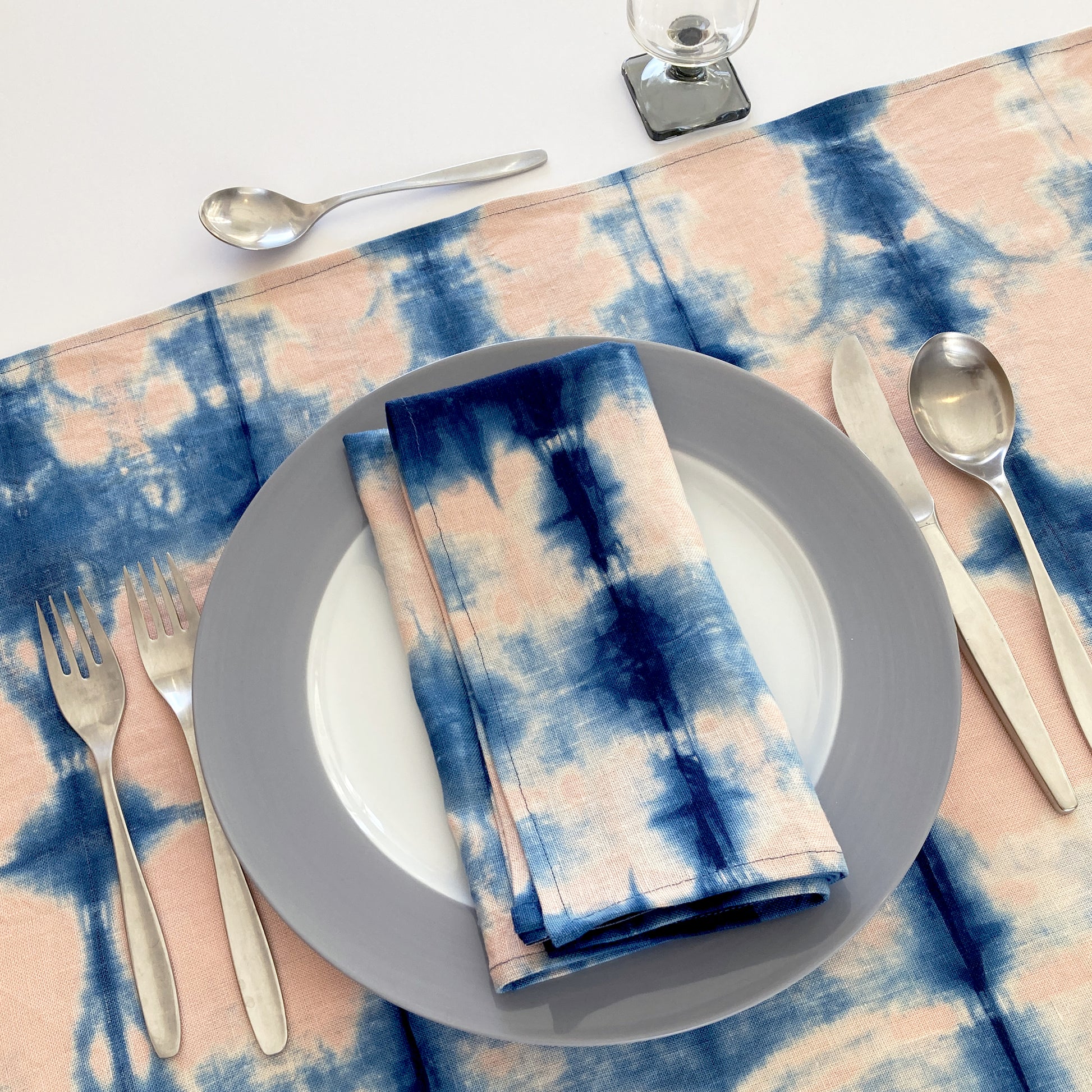 Rose pink linen table runner dyed with indigo in Pleat pattern, shown here with matching napkin.