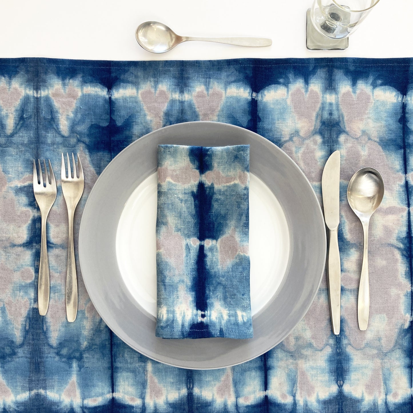 Silver gray linen table runner dyed with indigo in Pleat pattern, shown here with matching napkin.