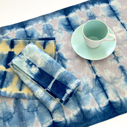 Silver gray linen table runner dyed with indigo in Pleat pattern, shown here with napkins in gold and jade.