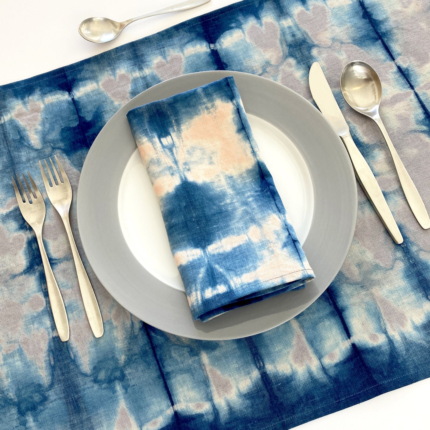 Silver gray linen table runner dyed with indigo in Pleat pattern, shown here with napkin in rose.