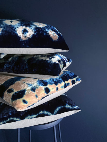 Grouping of rose and indigo velvet pillows in abstract patterns. Navy background.