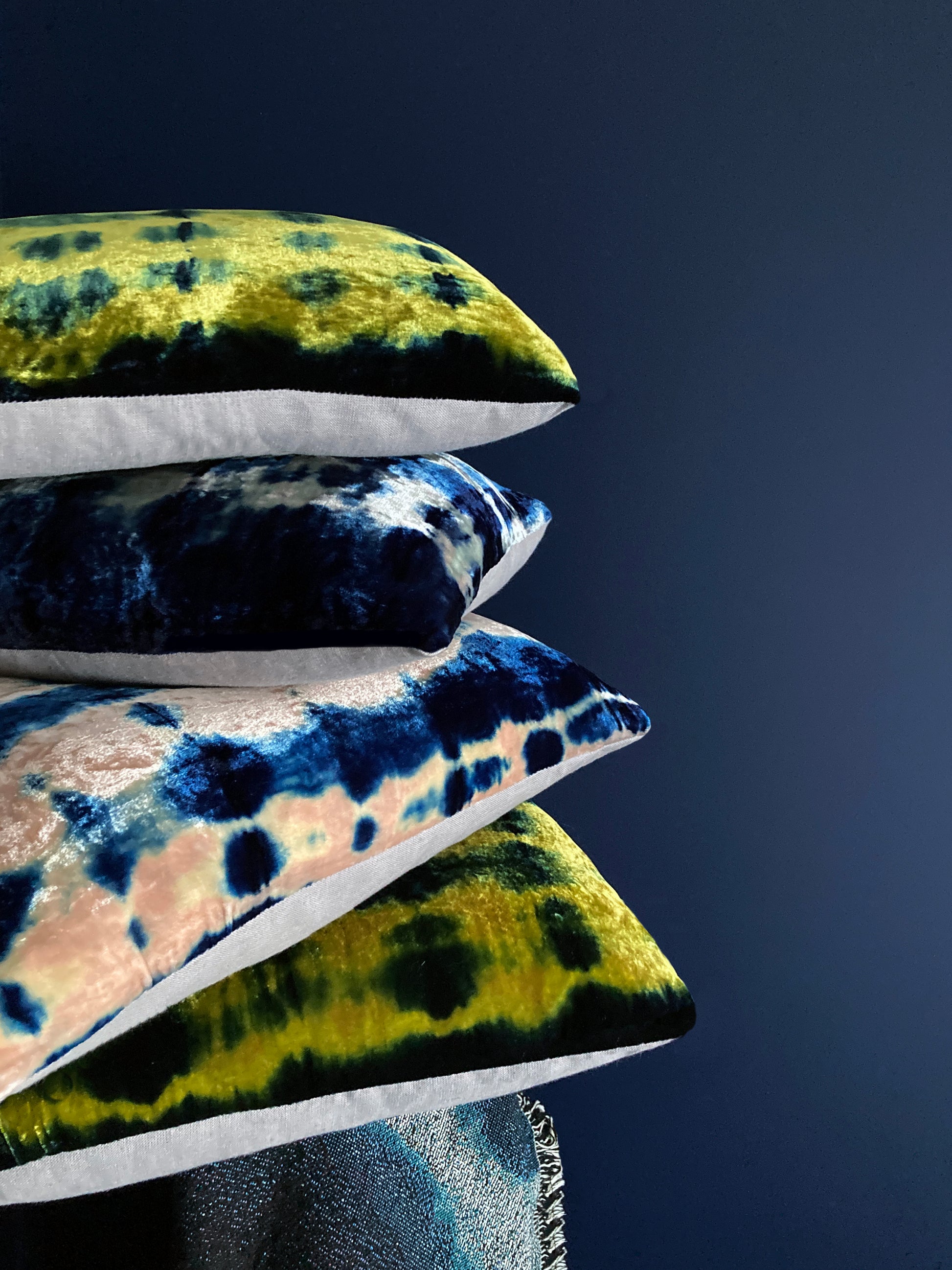 Grouping of gold, pink, silver and indigo velvet pillows in abstract patterns.