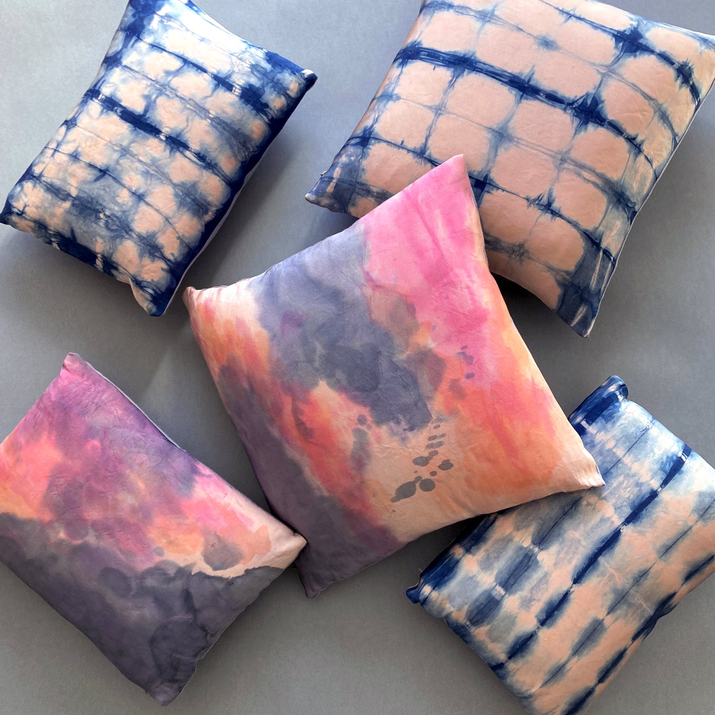 Grouping of rose pink silk pillows in abstract patterns.