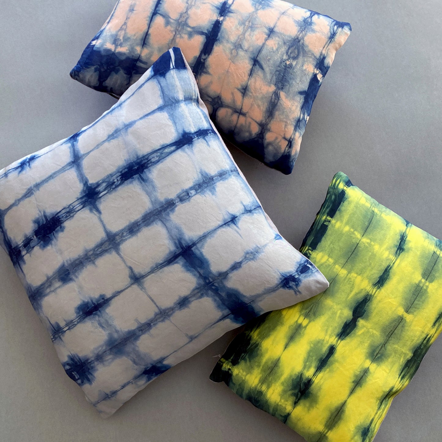 Canary yellow, pink and gray silk pillows dyed with indigo, in abstract patterns.