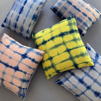 Canary yellow, pink and gray silk pillows dyed with indigo, in abstract patterns.