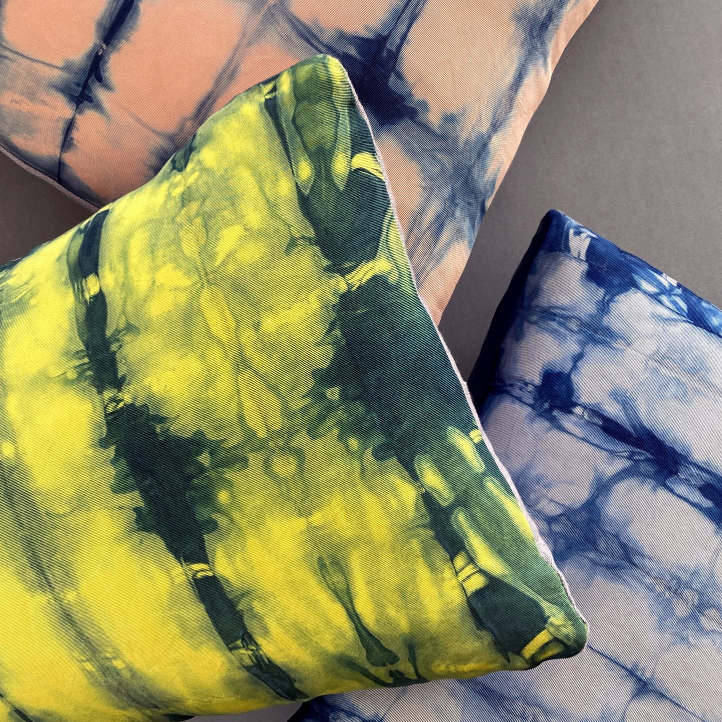 Canary yellow, pink and gray silk pillows dyed with indigo, in abstract patterns.