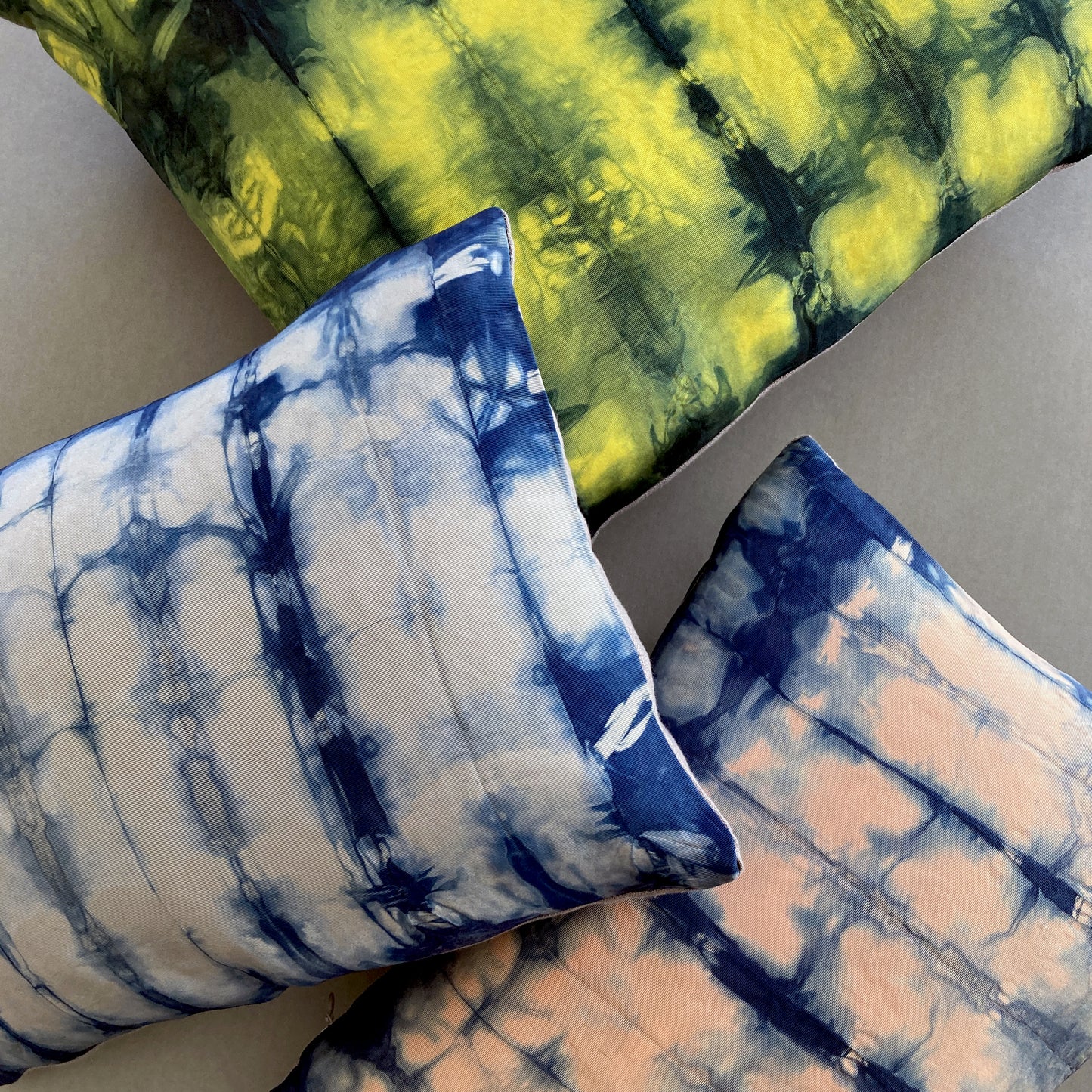 Canary yellow, pink and gray silk pillows dyed with indigo, in abstract patterns.