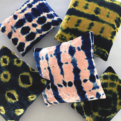 Grouping of gold, pink and indigo velvet pillows in abstract patterns.