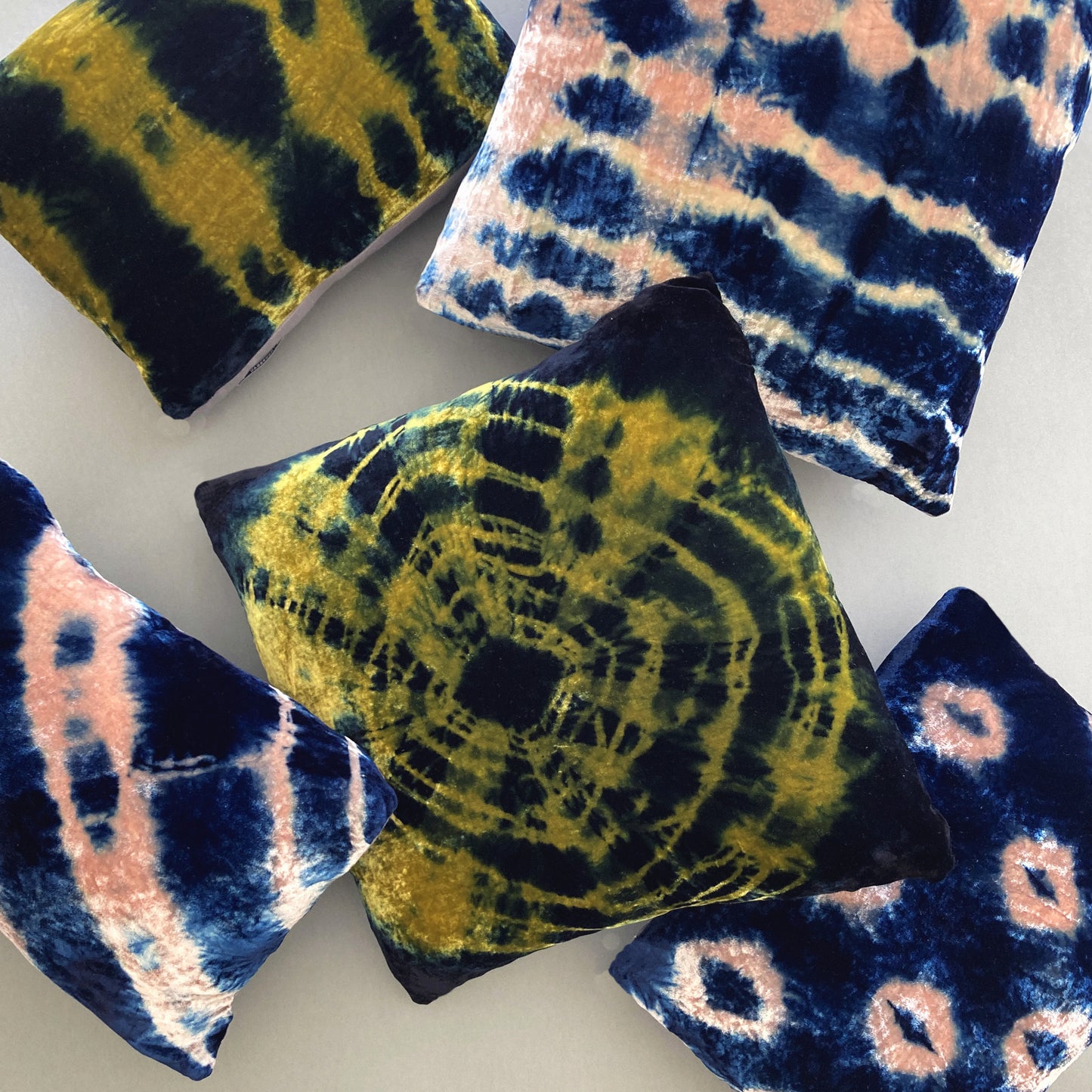 Grouping of gold, pink and indigo velvet pillows in abstract patterns.