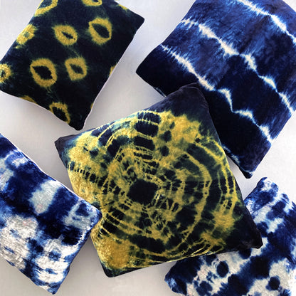 Grouping of gold, silver and indigo velvet pillows in abstract patterns.