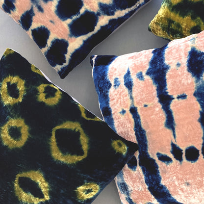 Grouping of gold, pink and indigo velvet pillows in abstract patterns.