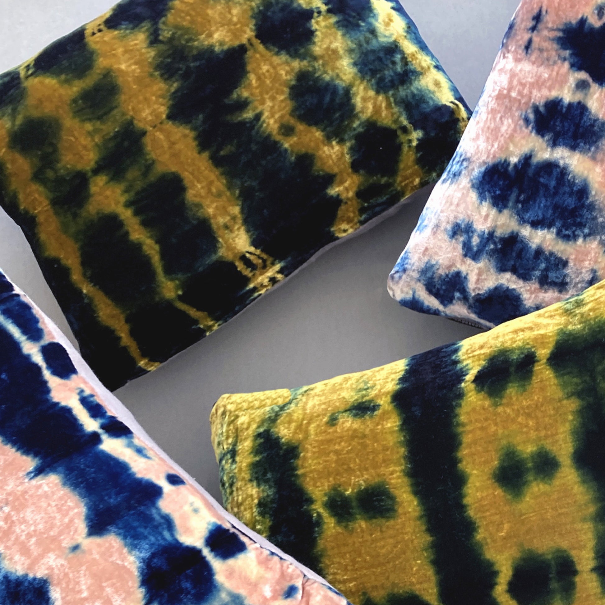 Grouping of gold, pink and indigo velvet pillows in abstract patterns.