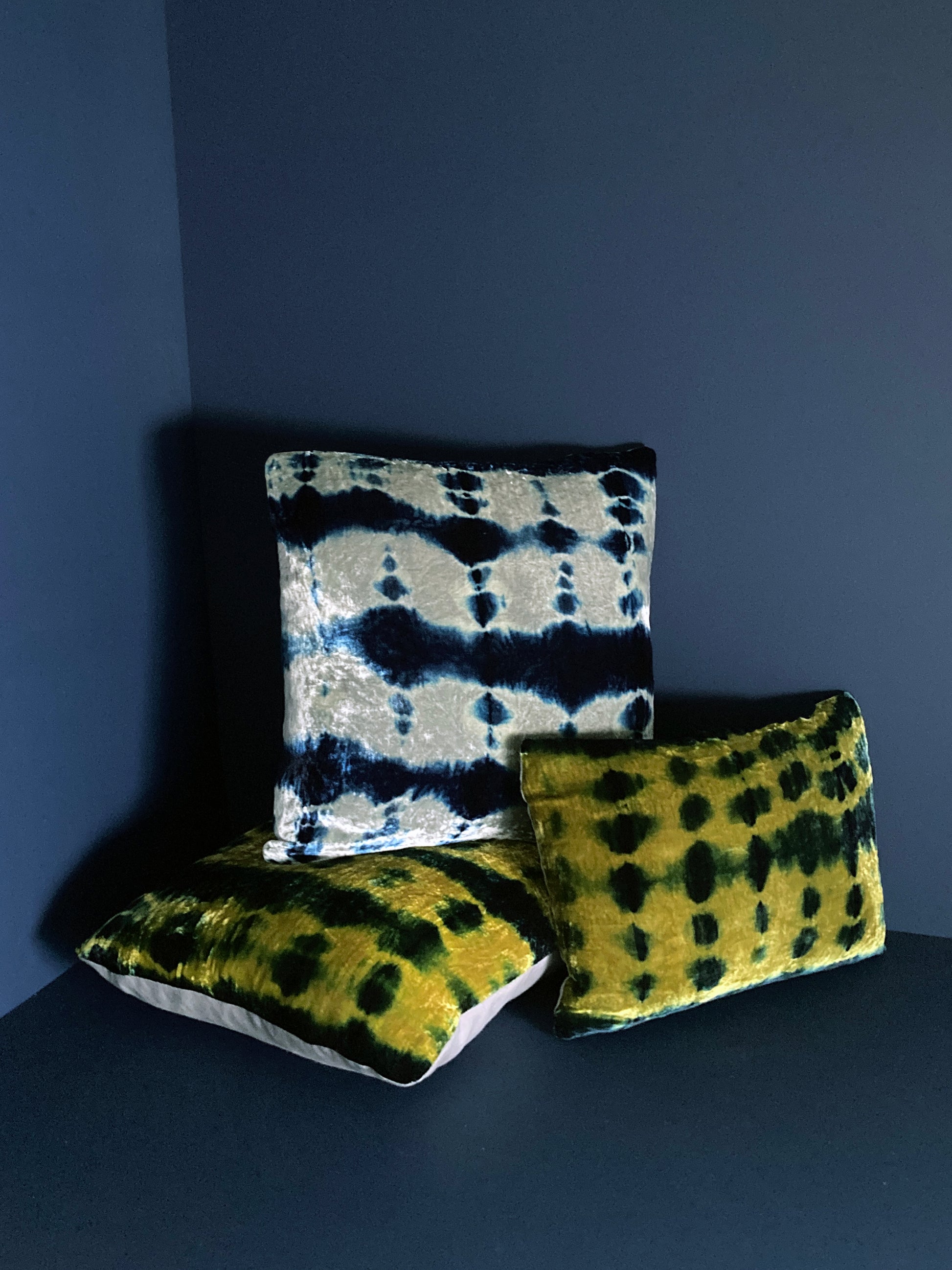 Grouping of gold, silver and indigo velvet pillows in abstract patterns.