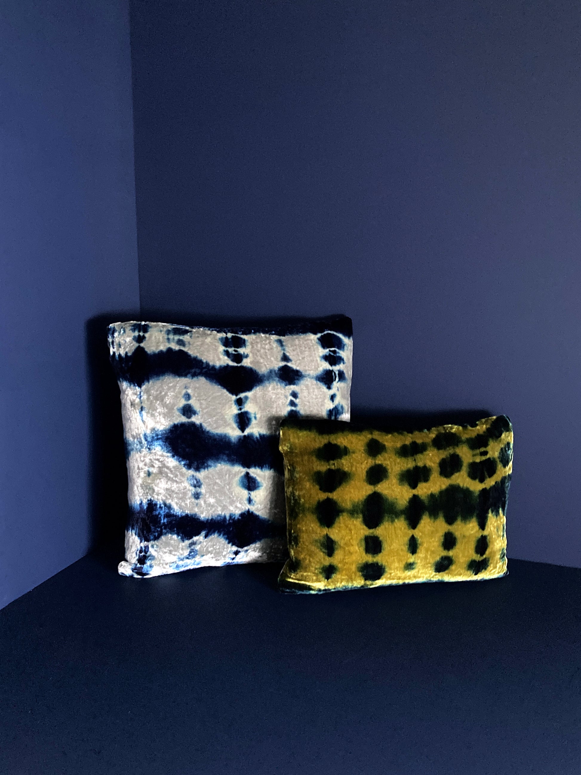 Grouping of gold, silver and indigo velvet pillows in abstract patterns.