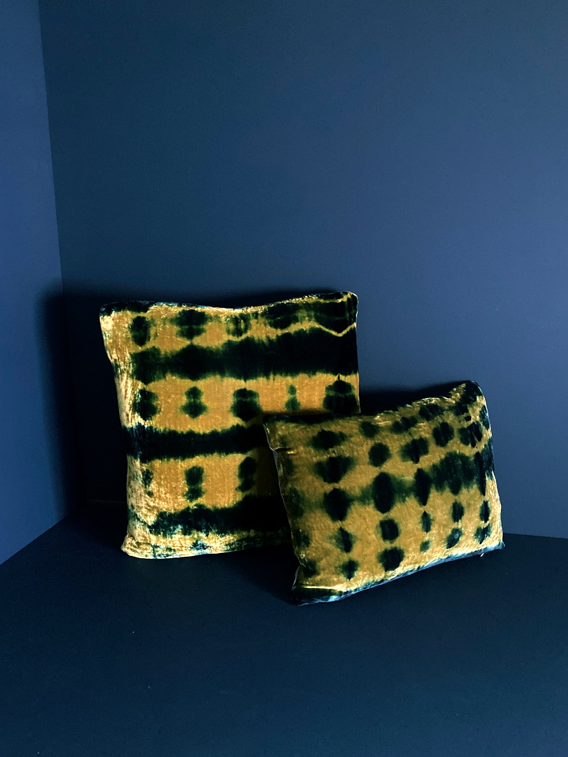 Grouping of gold and indigo velvet pillows in abstract patterns.