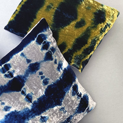 Grouping of gold, silver and indigo velvet pillows in abstract patterns.