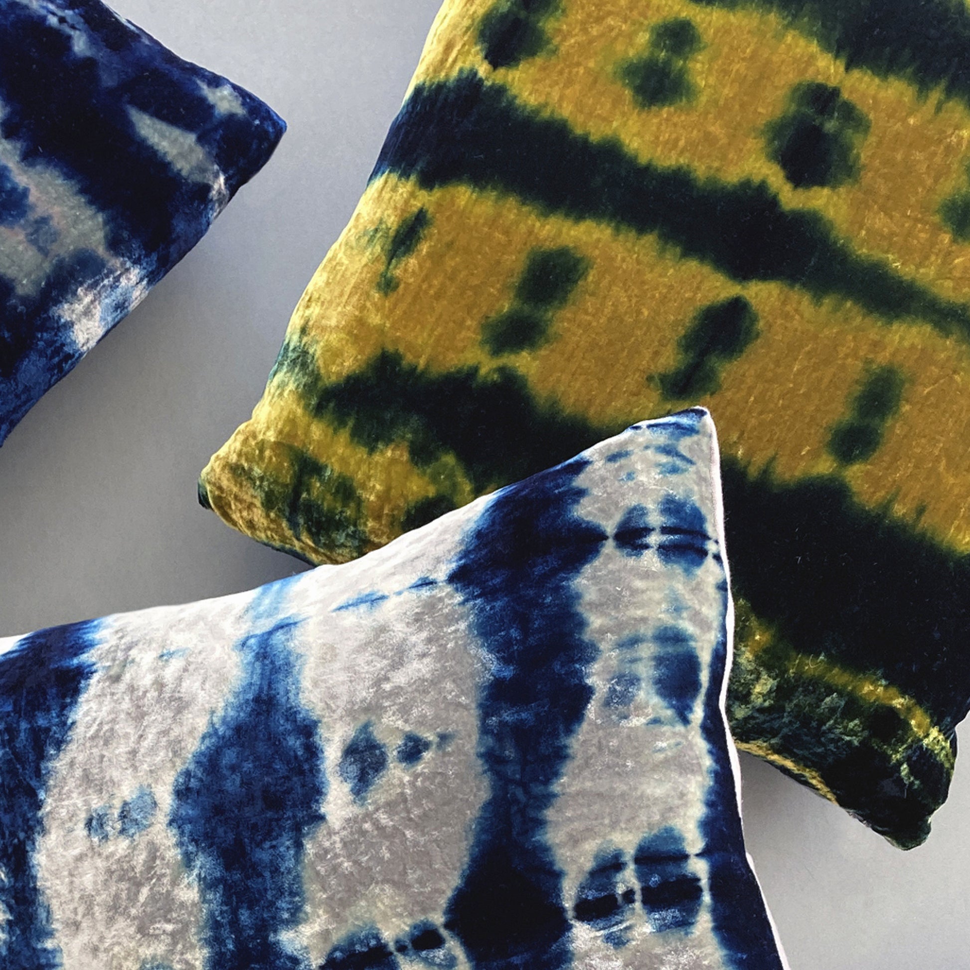 Grouping of gold, silver and indigo velvet pillows in abstract patterns.