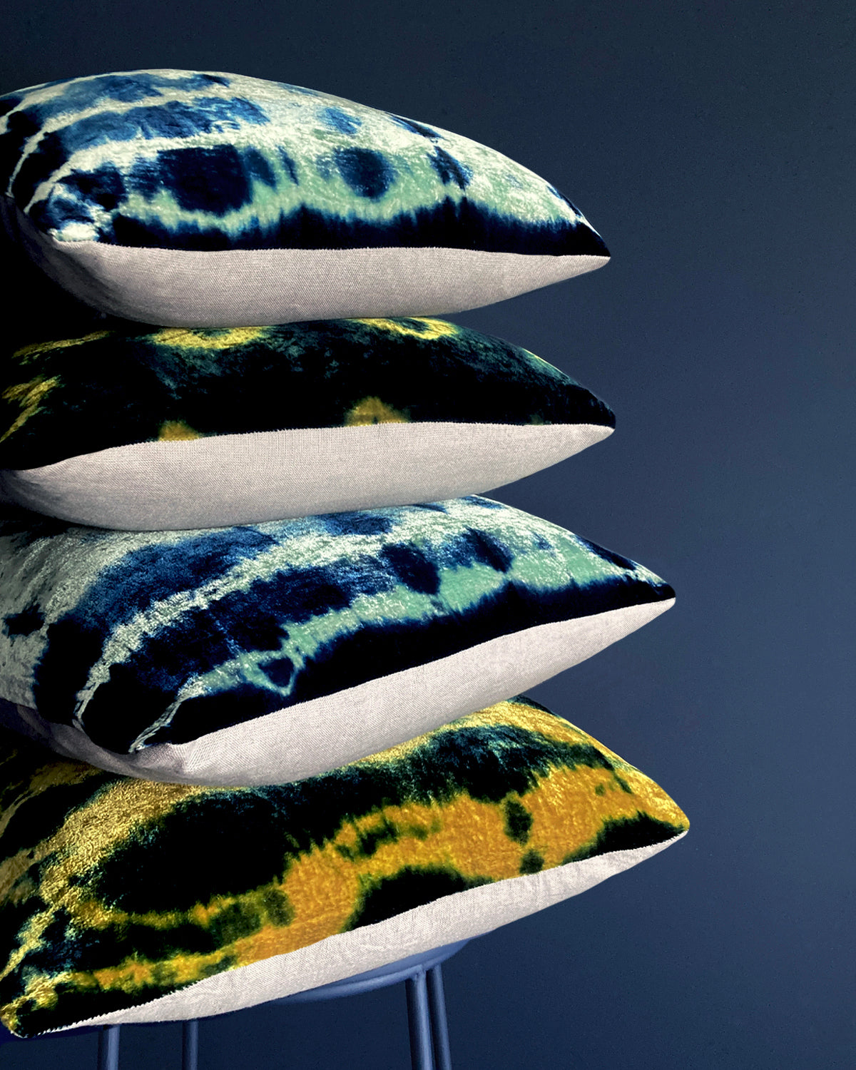 Grouping of gold, jade and indigo velvet pillows in abstract patterns.