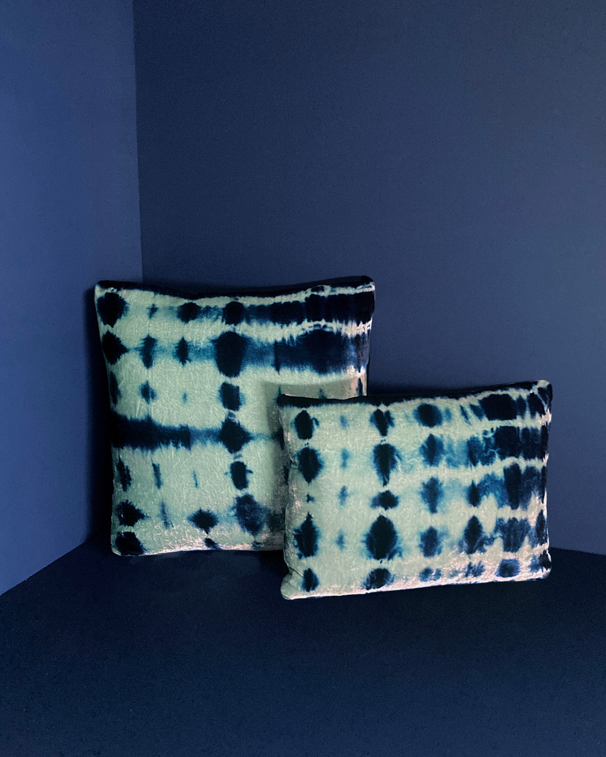 Grouping of jade and indigo velvet pillows in abstract patterns.