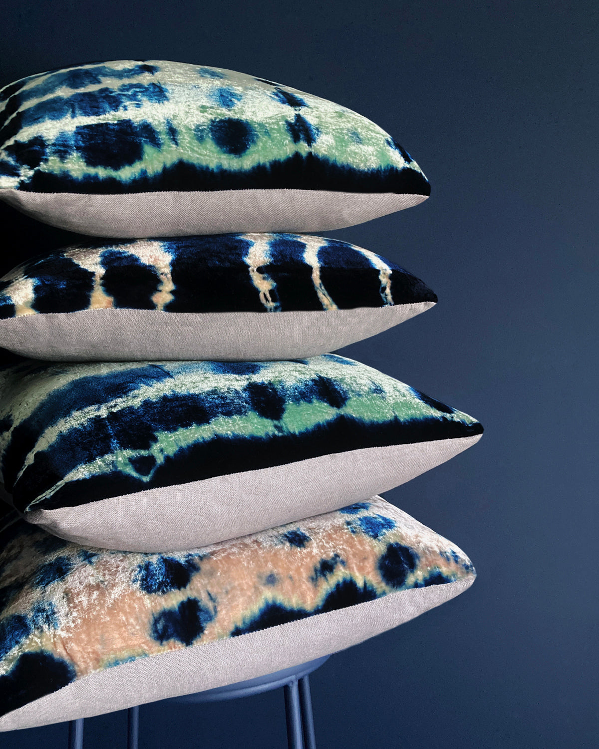 Grouping of jade, pink and indigo velvet pillows in abstract patterns.