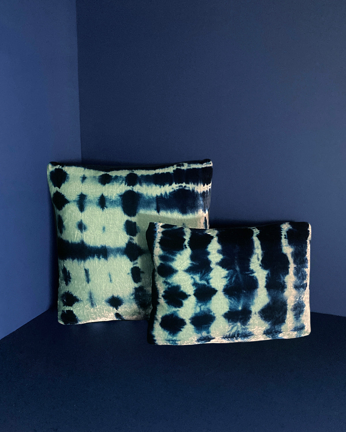 Grouping of jade and indigo velvet pillows in abstract patterns.