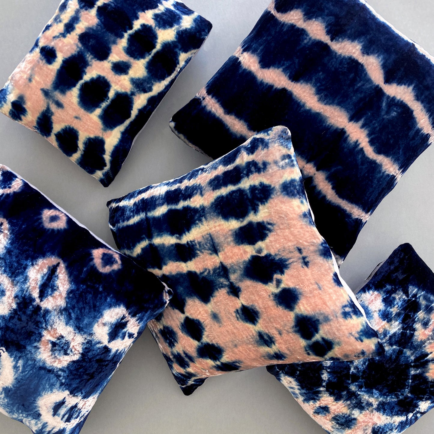 Grouping of rose and indigo velvet pillows in abstract patterns.