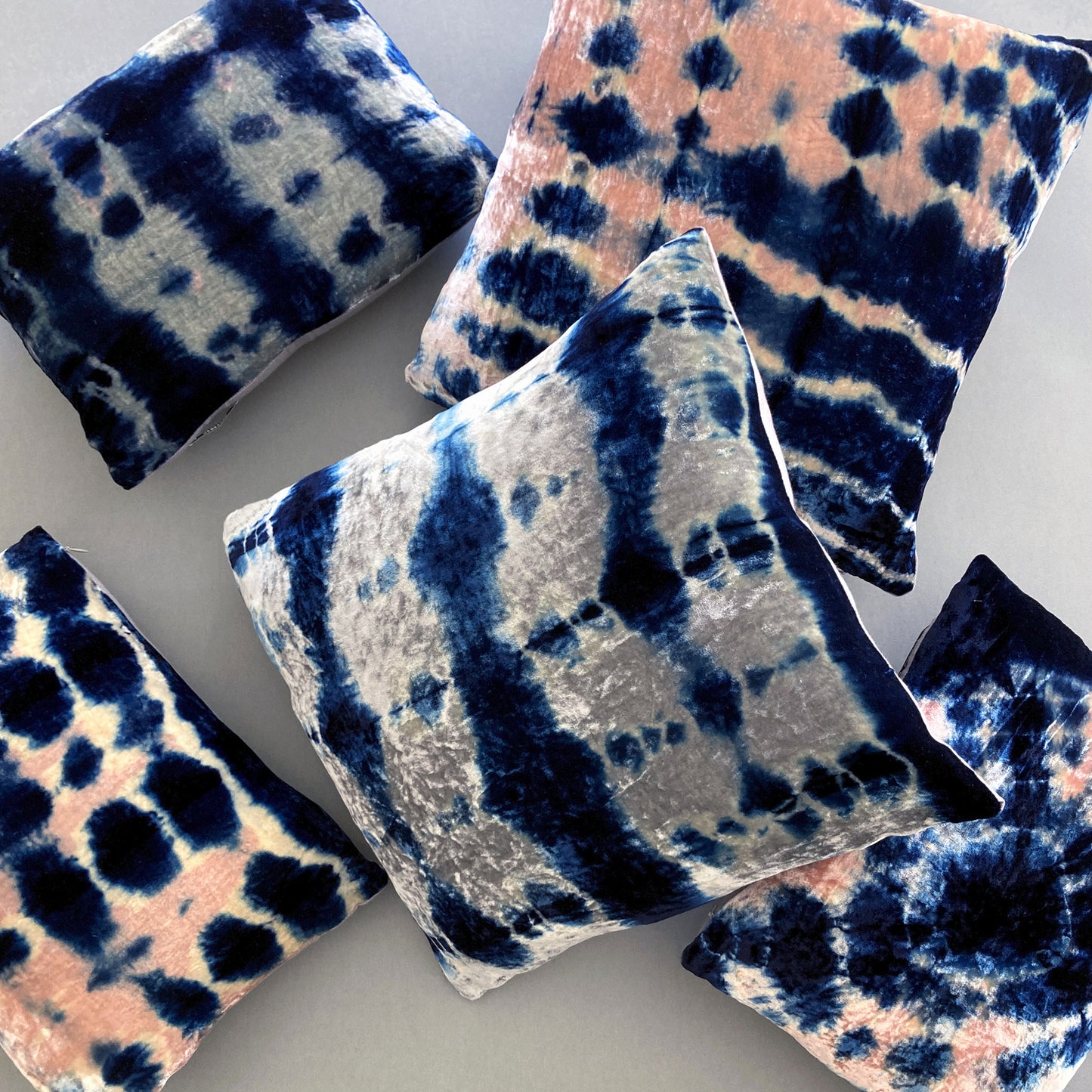 Grouping of rose, silver and indigo velvet pillows in abstract patterns.