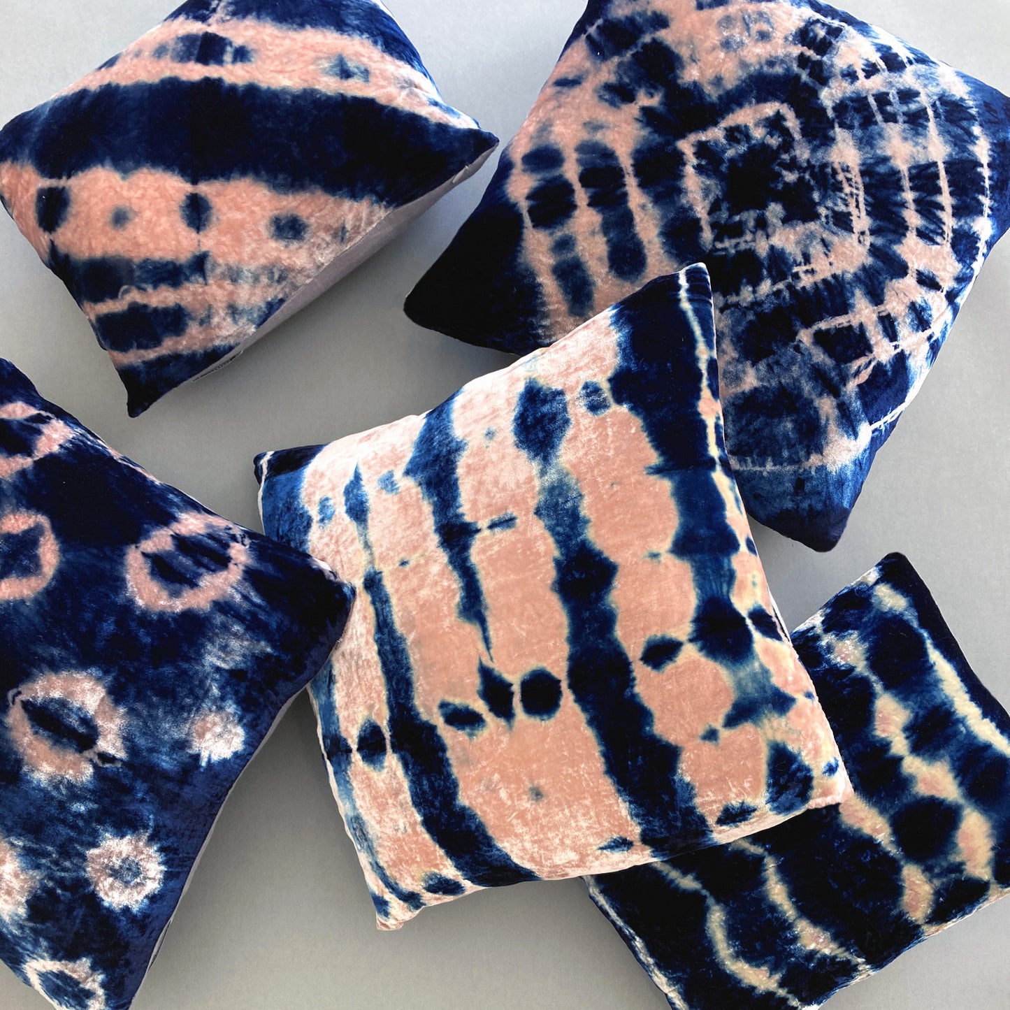 Grouping of rose and indigo velvet pillows in abstract patterns.