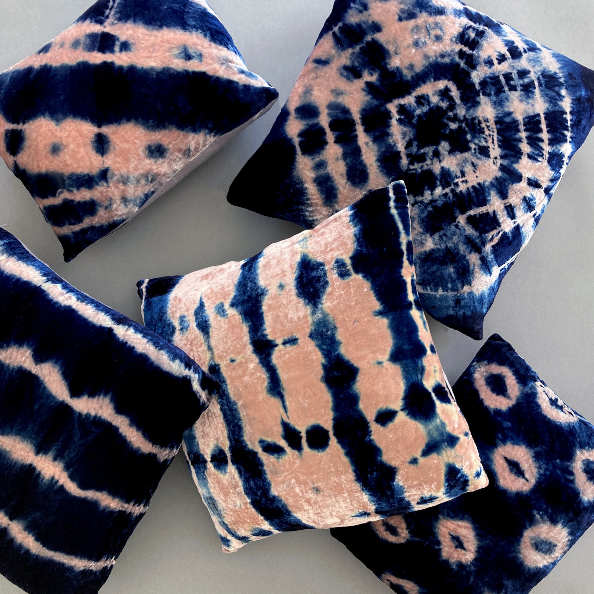 Grouping of rose and indigo velvet pillows in abstract patterns.