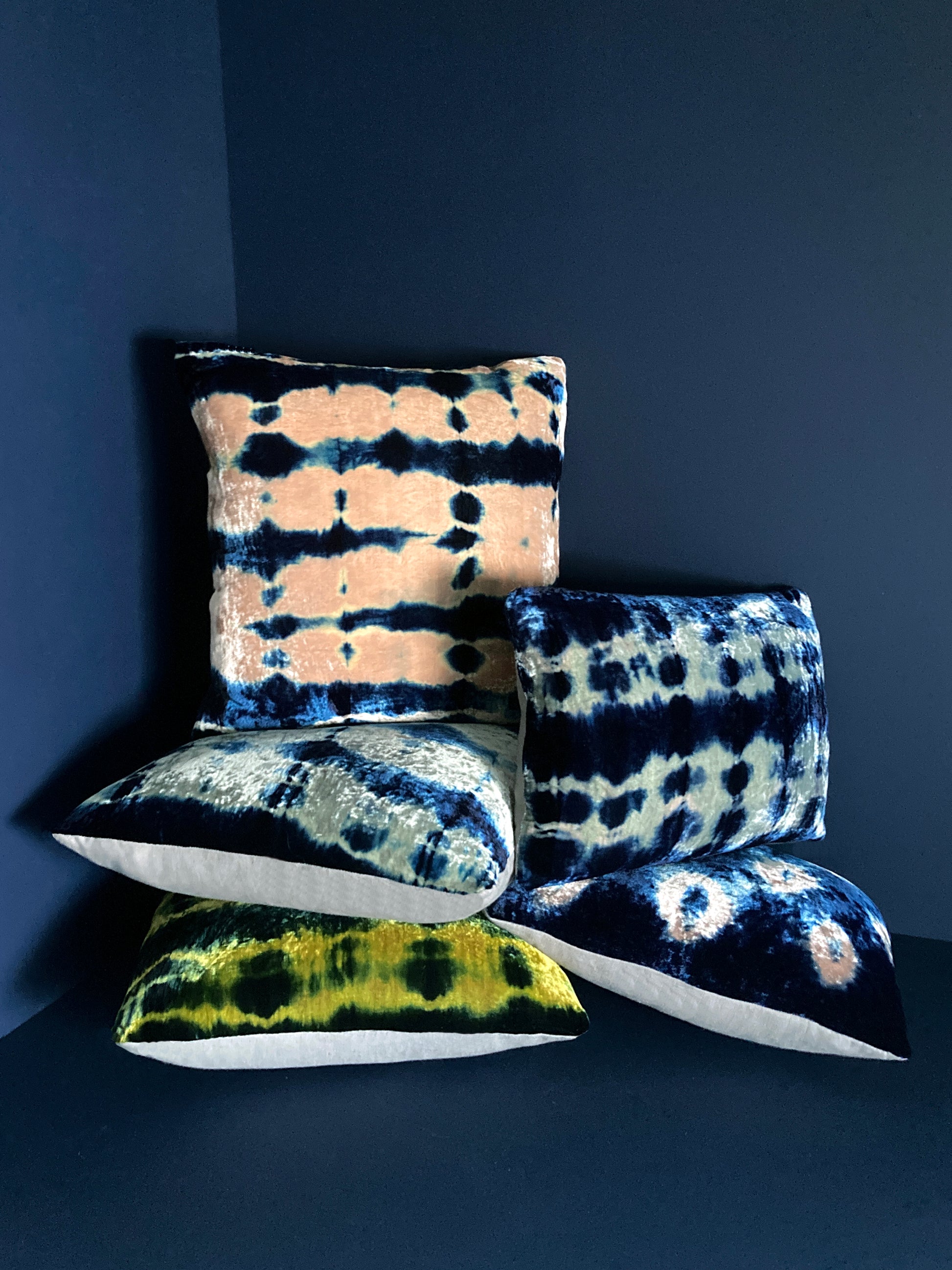 Grouping of gold, pink, silver and indigo velvet pillows in abstract patterns.