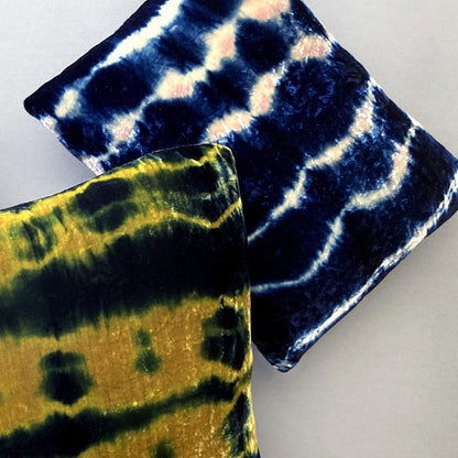 Grouping of gold, pink and indigo velvet pillows in abstract patterns.