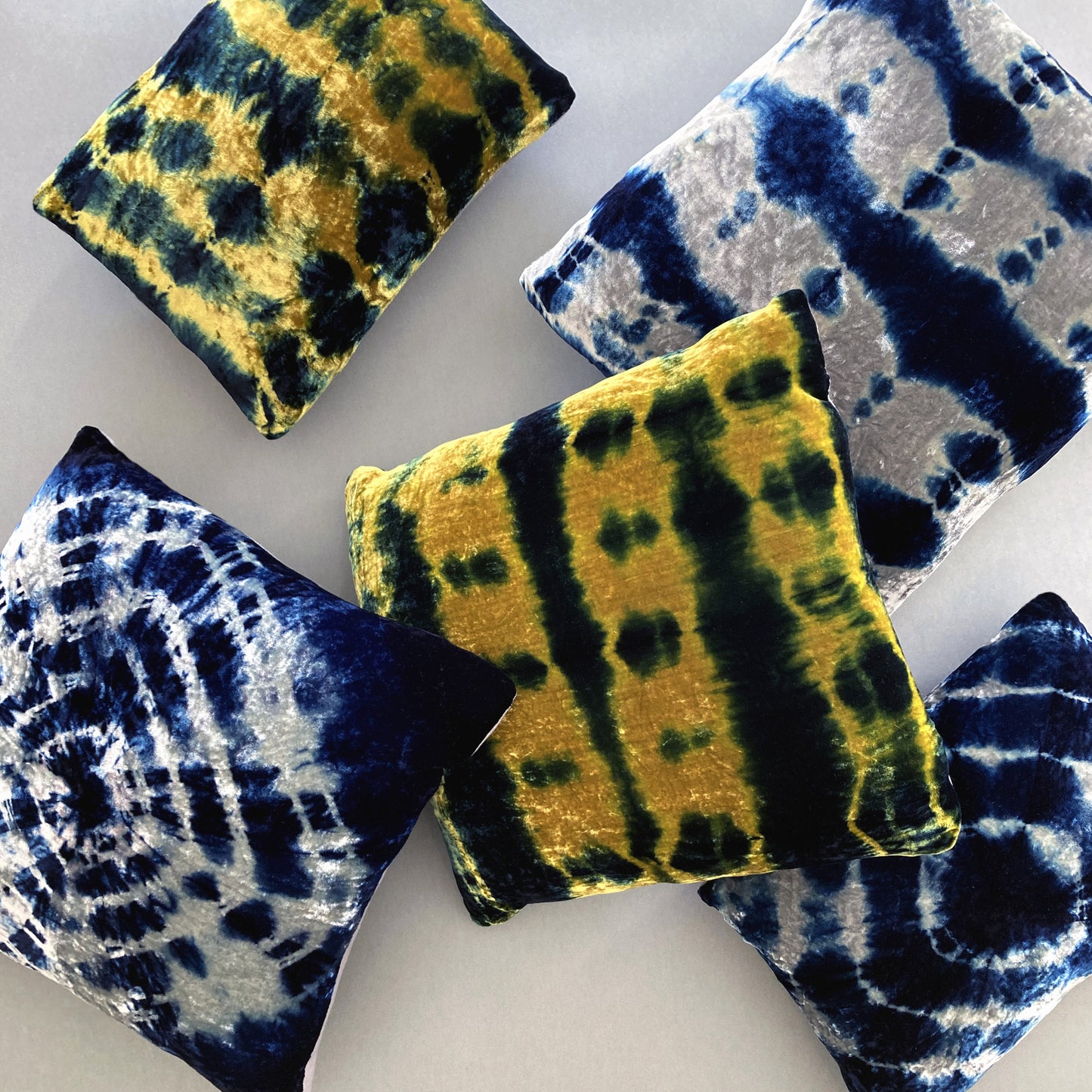 Grouping of gold, silver and indigo velvet pillows in abstract patterns.