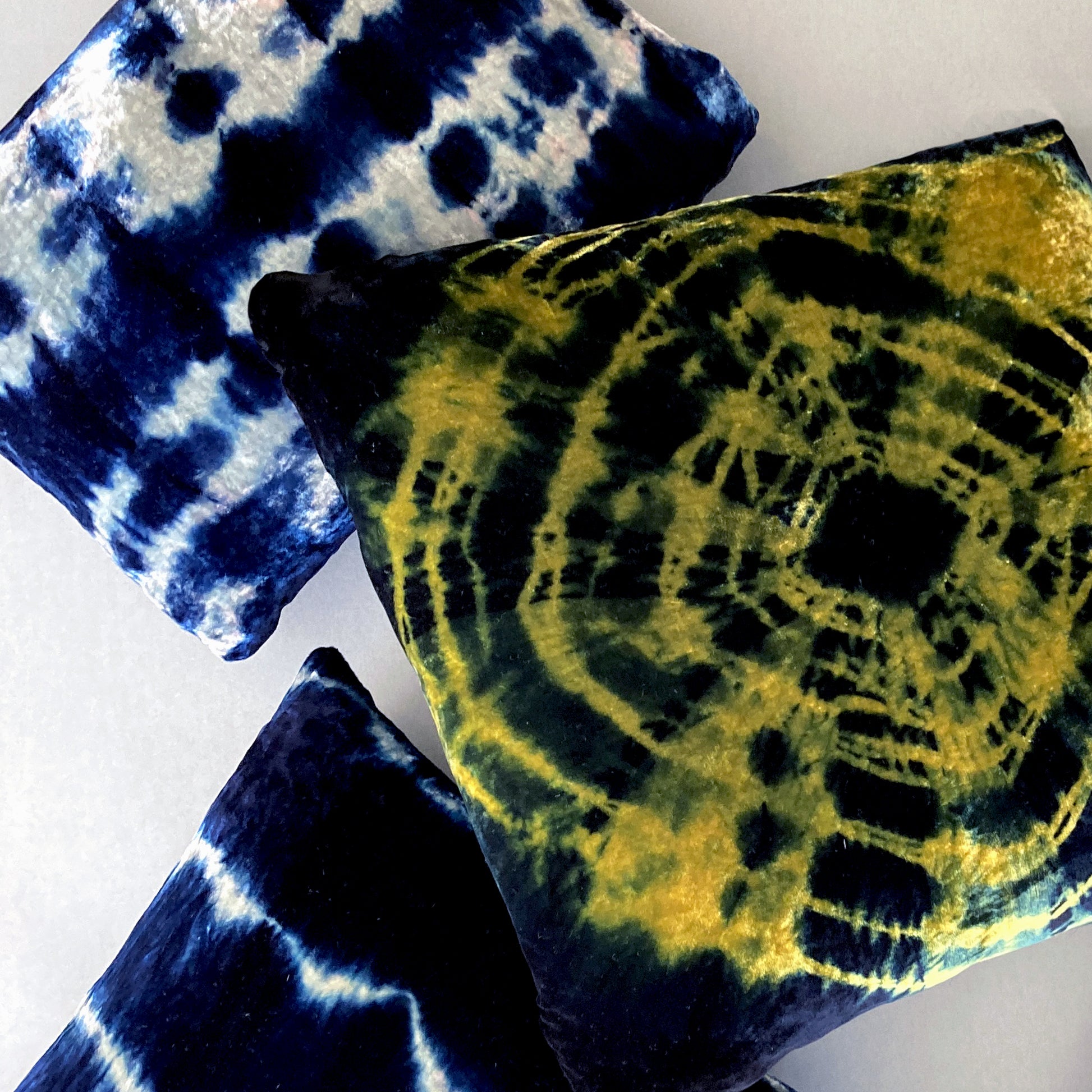 Grouping of gold, silver and indigo velvet pillows in abstract patterns.