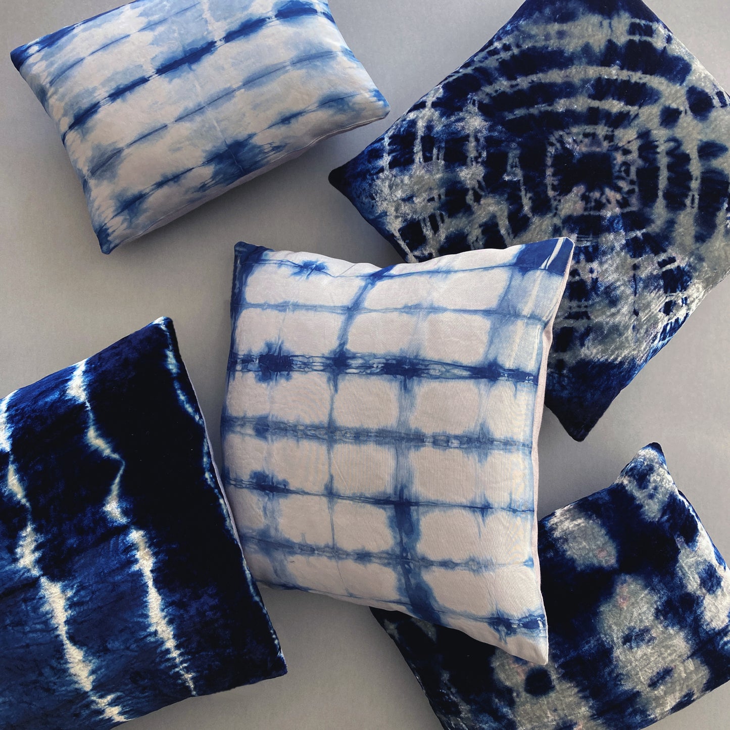 Grouping of silver and indigo silk and velvet pillows in abstract patterns.