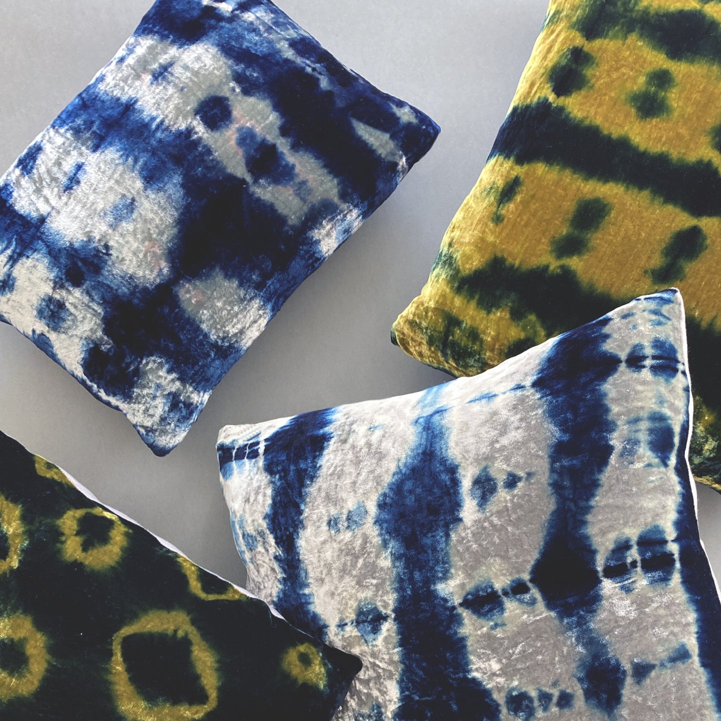 Grouping of gold, silver and indigo velvet pillows in abstract patterns.