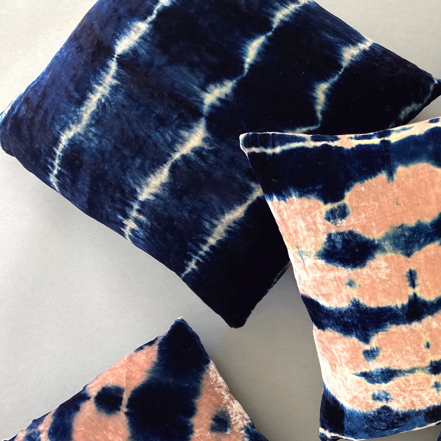 Grouping of silver, pink and indigo velvet pillows in abstract patterns.