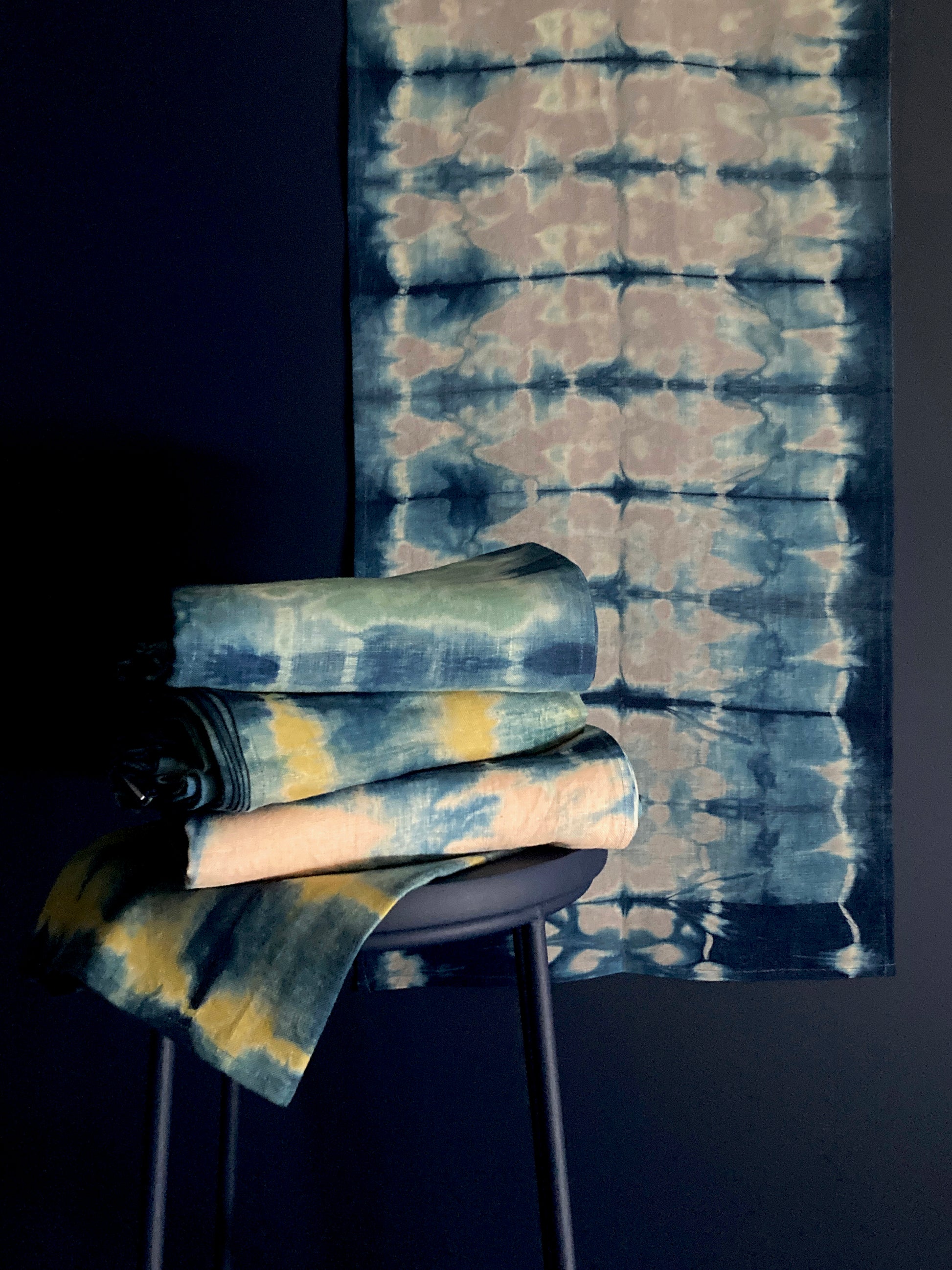 A grouping of table linens in silver gray, jade green, gold mustard, and rose pink.