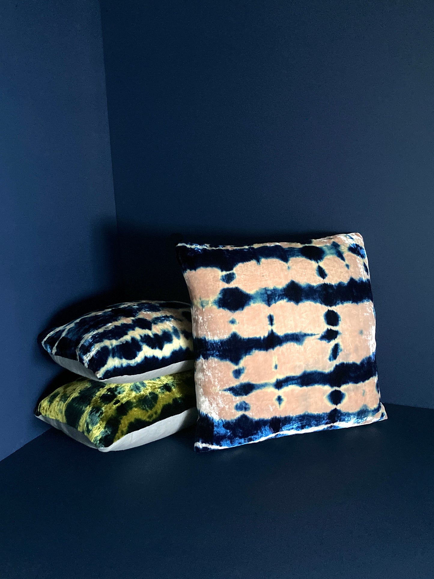 Grouping of gold, pink and indigo velvet pillows in abstract patterns.